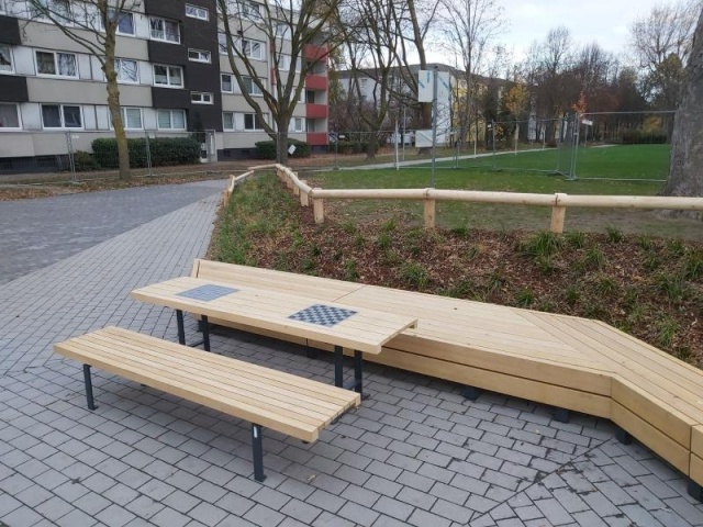 euroform w - Stadtmobiliar - lange gewinkelte Bank aus Hartholz bei öffentlichem Park - Parktisch für draußen - Lineatavolo Tisch aus Hartholz für den öffentlichen Raum