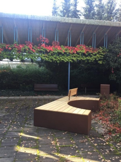 euroform w - Stadtmobiliar - Sitzbank aus Holz und Cortenstahl auf öffentlichem Platz - Parkbank mit Rückenlehne - Sitzinsel in Innenhof im Grünen - Isola