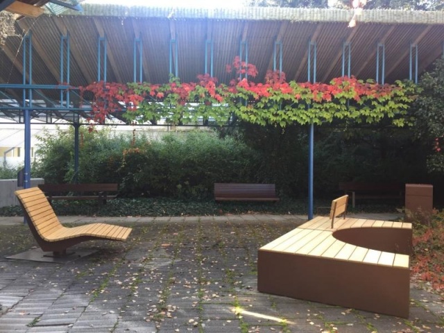 euroform w - Stadtmobiliar - Sitzbank aus Holz und Cortenstahl auf öffentlichem Platz - Parkbank mit Rückenlehne - Sitzinsel in Innenhof im Grünen - Isola