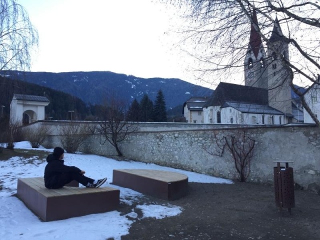 euroform w - Stadtmobiliar - Sitzbank aus Holz und Cortenstahl auf öffentlichem Platz - Parkbank ohne Rückenlehne - Menschen auf Sitzinsel in Innenhof im Grünen - Isola