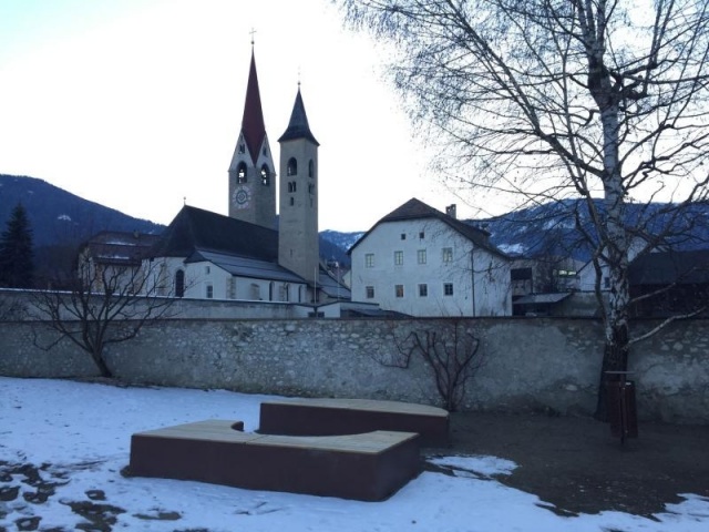 euroform w - Stadtmobiliar - Sitzbank aus Holz und Cortenstahl auf öffentlichem Platz - Parkbank ohne Rückenlehne - Sitzinsel in Innenhof im Grünen - Isola