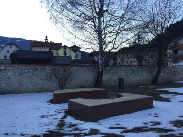 euroform w - Stadtmobiliar - Sitzbank aus Holz und Cortenstahl auf öffentlichem Platz - Parkbank ohne Rückenlehne - Sitzinsel in Innenhof im Grünen - Isola