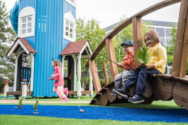 Parco giochi - Lappset - la casa dei Moomins torre gigante su prato con bambini - Parco divertimenti Moomins con ponte e stagno dei pesci in parco pubblico con bambini