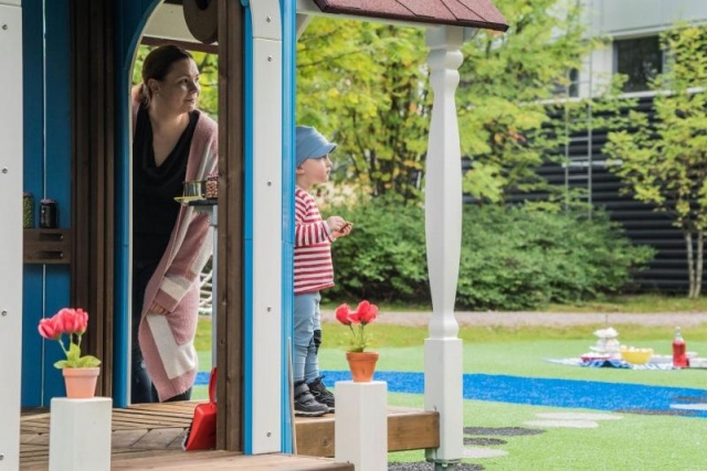 Spielplatz - Lappset - Moomins gigantisches Spielhaus auf Wiese mit Kindern – Freizeitpark Moomins mit Brücke und Fischteich in öffentlichem Park mit Kindern