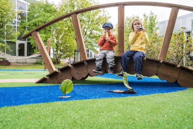 Parco giochi - Lappset - la casa dei Moomins torre gigante su prato con bambini - Parco divertimenti Moomins con ponte e stagno dei pesci in parco pubblico con bambini