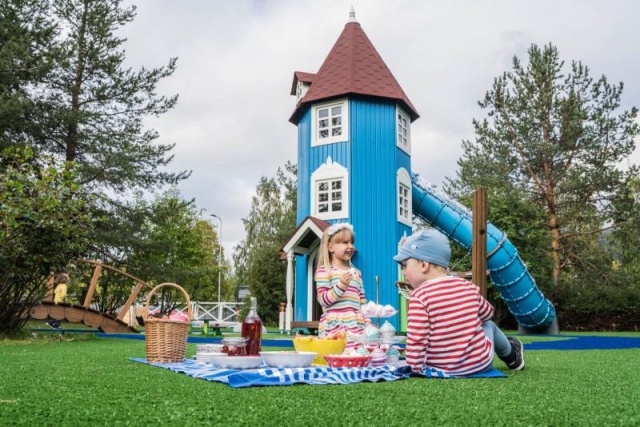 Spielplatz - Lappset - Moomins gigantisches Spielhaus auf Wiese mit Kindern – Freizeitpark Moomins in öffentlichem Park mit Kindern