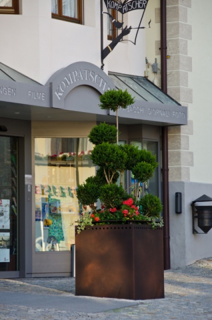 euroform w - Stadtmobiliar - große Pflanzschale aus Metall auf Dorfplatz - riesige Pflanzschale mit Blumen und Baum in urbanem Raum - Pflanzschale aus Cortenstahl