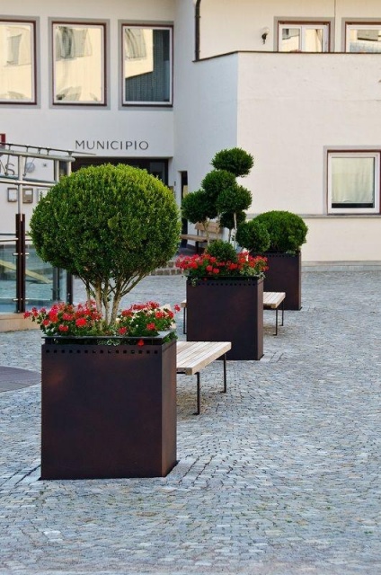 euroform w - Stadtmobiliar - große Pflanzschale aus Metall auf Dorfplatz - riesige Pflanzschale mit Blumen und Baum in urbanem Raum - Pflanzschale aus Cortenstahl