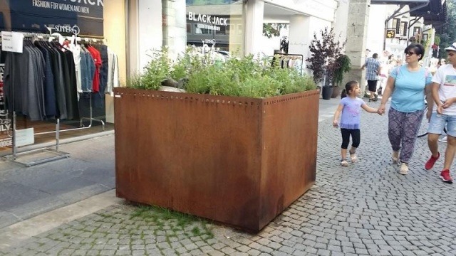 euroform w - Stadtmobiliar - große Pflanzschale aus Metall auf Dorfplatz - riesige Pflanzschale mit Blumen und Baum in urbanem Raum - Pflanzschale aus Cortenstahl