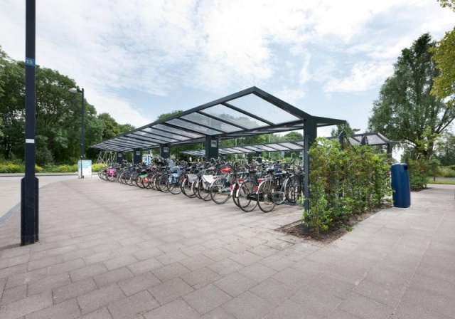 euroform w - Freiraummobiliar - Klaver - Fahrradüberdachung aus Stahl und Glas - Fahrradständer mit Fahrrädern auf öffentlichem Platz