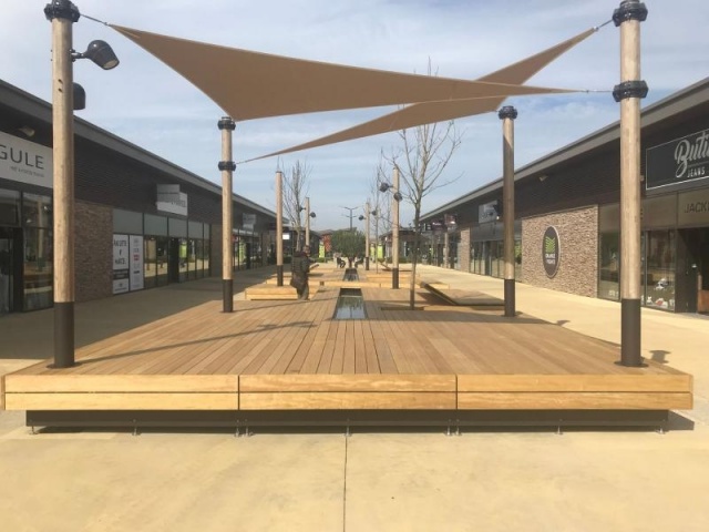 euroform w - sustainable street furniture - seating island in shopping centre - modular seating with shade sail, trees and water - wooden lounger with shade dispenser - bench with indirect lighting