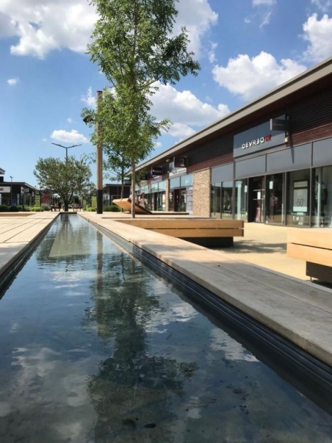 euroform w - sustainable street furniture - seating island in shopping centre - modular seating with shade sail, trees and water - wooden lounger with shade dispenser - bench with indirect lighting