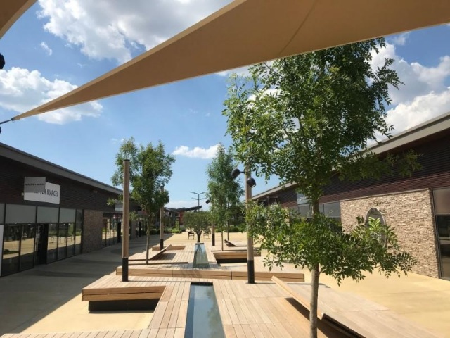 euroform w - nachhaltiges Stadtmobiliar - Sitzinsel in Einkaufzentrum - modulare Sitzgelegenheit mit Sonnensegel, Bäumen und Wasser - Liege aus Holz mit Schattenspender