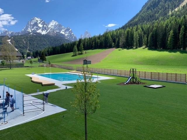 euroform w - Stadtmobiliar - Bank Isola aus Holz im Freibad Sexten mit Blick auf Dolomiten - Sitzbank in Freibad Sexten - Parkbank aus Holz mit Blick auf Dolomiten