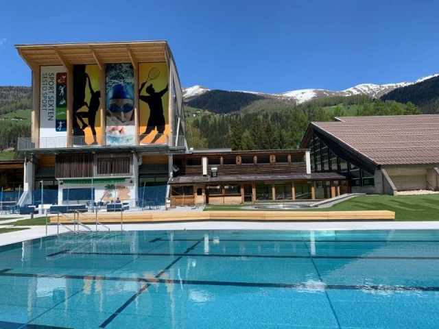 euroform w - Stadtmobiliar - Bank Isola aus Holz im Freibad Sexten mit Blick auf Dolomiten - Sitzbank in Freibad Sexten - Parkbank aus Holz mit Blick auf Dolomiten