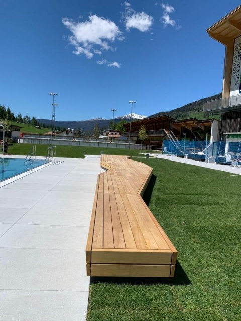 euroform w - Stadtmobiliar - Bank Isola aus Holz im Freibad Sexten mit Blick auf Dolomiten - Sitzbank in Freibad Sexten - Parkbank aus Holz mit Blick auf Dolomiten