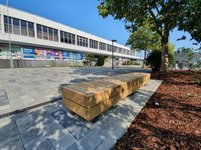 euroform w - Stadtmobiliar - lang gewinkelte Bank aus Holz auf Stadtplatz - Designerbank aus Holz für draußen - Sitzinsel aus Holz für städtischen Raum - Isola hochwertige Stadtmöbel für Bahnhof Cottbus