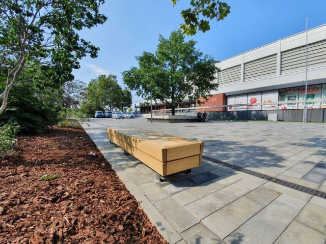 euroform w - Stadtmobiliar - lang gewinkelte Bank aus Holz auf Stadtplatz - Designerbank aus Holz für draußen - Sitzinsel aus Holz für städtischen Raum - Isola hochwertige Stadtmöbel für Bahnhof Cottbus