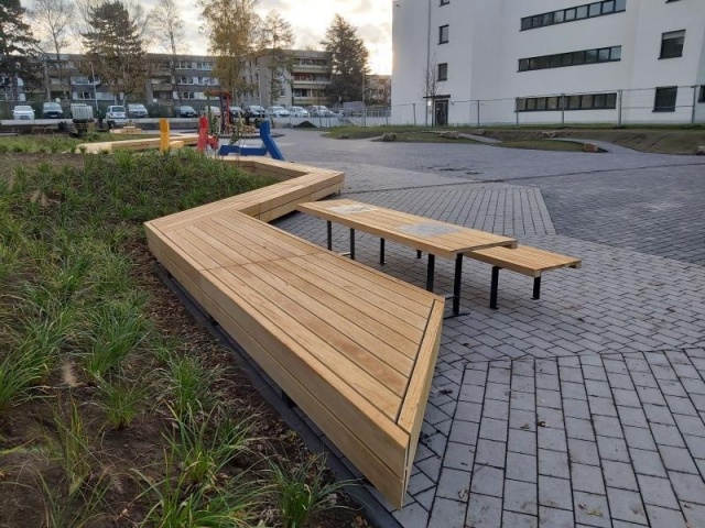 euroform w - Stadtmobiliar - lange gewinkelte Bank aus Hartholz bei öffentlichem Park - Parktisch für draußen - Lineatavolo Tisch aus Hartholz für den öffentlichen Raum