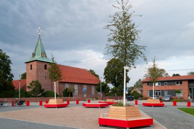 euroform w - Stadtmobiliar - eckige Bank aus Holz und buntem Metall auf öffentlichem Platz in Weyhe - Sitzinsel für den öffentlichen Raum - Bank mit Baum in Mitte - customized Stadtmöbel  für Weyhe Deutschland