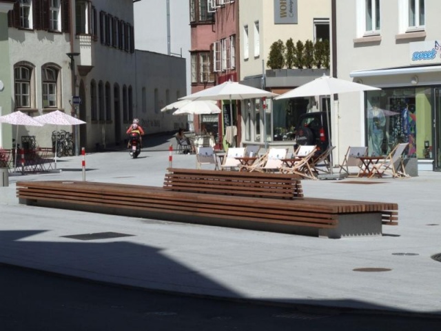 euroform w - Stadtmobiliar - minimalistische Bank aus Holz und Beton mit indirekter Beleuchtung bei Wiltener Platzl in Innsbruck - Sitzinsel aus Holz und Beton auf öffentlichem Platz in Österreich - customized Stadtmöbel - Sonderlösung für den urbanen Rau