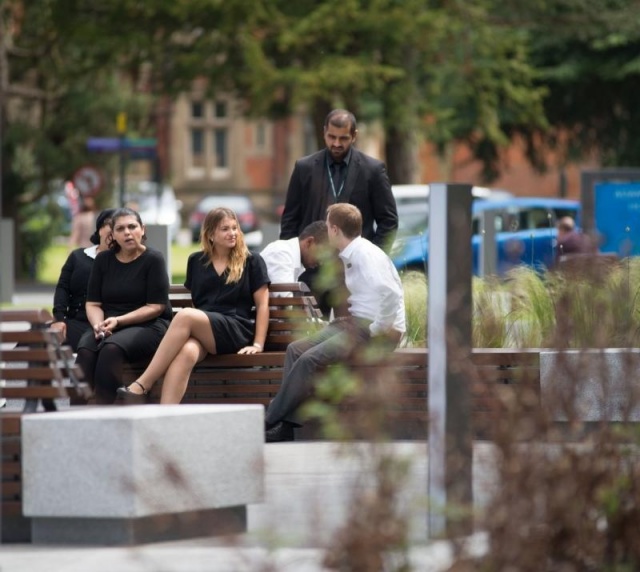 euroform w - arredo urbano - persone sedute su panchina minimalista in legno e cemento su piazza pubblica a Didsbury in Inghilterra - isola di sedute in legno e cemento in parco pubblico in Inghilterra - arredo urbano personalizzato
