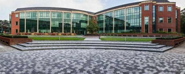 euroform w - arredo urbano - persone sedute su panchina minimalista in legno e cemento su piazza pubblica a Didsbury in Inghilterra - isola di sedute in legno e cemento in parco pubblico in Inghilterra - arredo urbano personalizzato