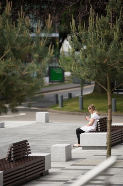 euroform w - street furniture - people sitting on minimalist bench made of wood and concrete on public square in Didsbury England - seating island made of wood and concrete in public park in England - customized street furniture