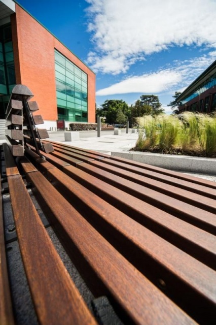 euroform w - arredo urbano - persone sedute su panchina minimalista in legno e cemento su piazza pubblica a Didsbury in Inghilterra - isola di sedute in legno e cemento in parco pubblico in Inghilterra - arredo urbano personalizzato