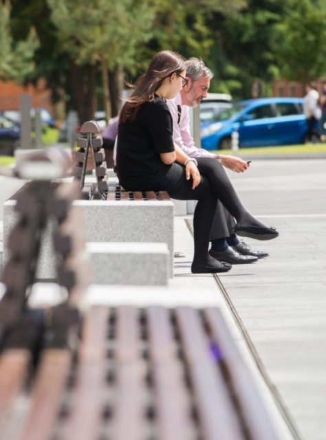 euroform w - arredo urbano - persone sedute su panchina minimalista in legno e cemento su piazza pubblica a Didsbury in Inghilterra - isola di sedute in legno e cemento in parco pubblico in Inghilterra - arredo urbano personalizzato