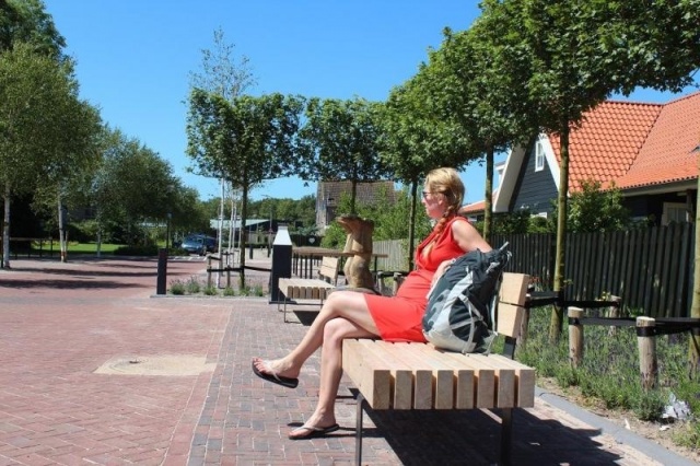euroform w - arredo urbano - donna su panchina in centro città in Ollanda - seduta in legno sostenibile - panchina su misura